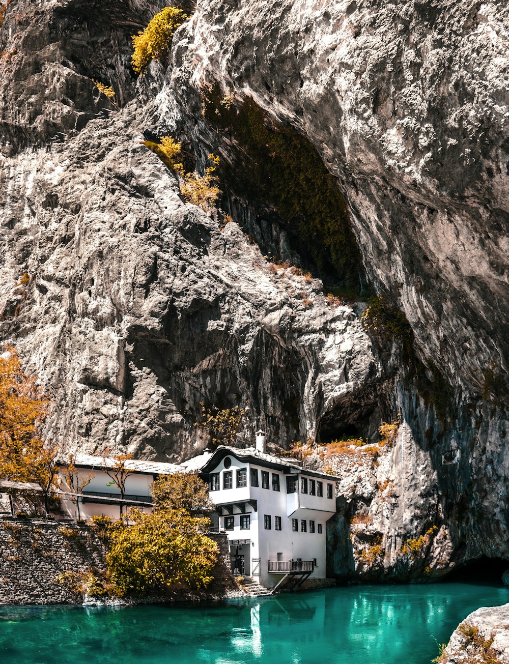 a house on the side of a mountain next to a body of water