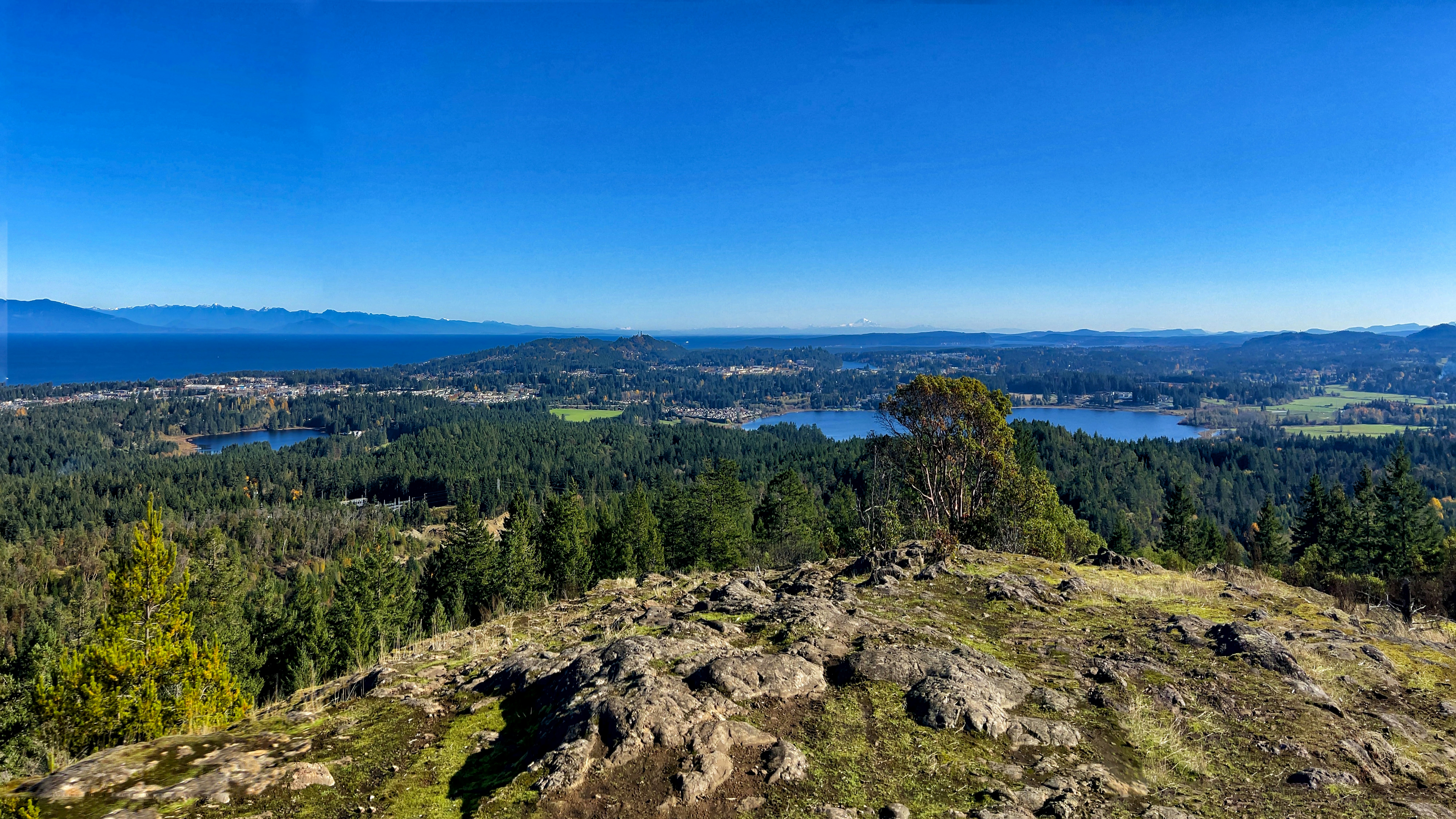 Rolling hills and lakes stretch toward distant coastal mountains.