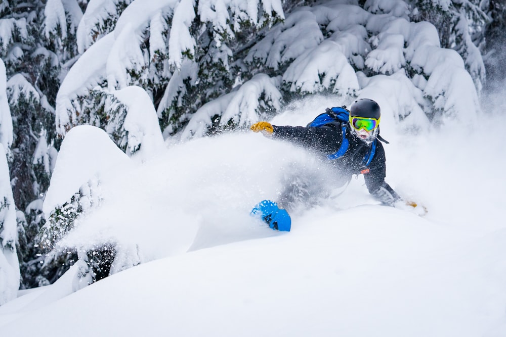 a man riding a snowboard down a snow covered slope