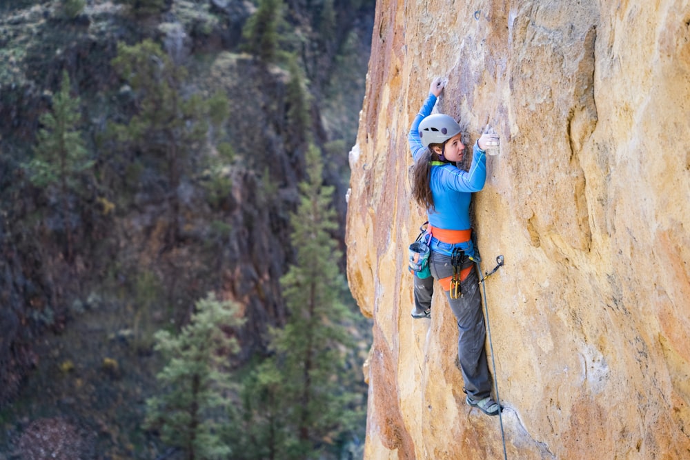 a woman climbing up the side of a cliff