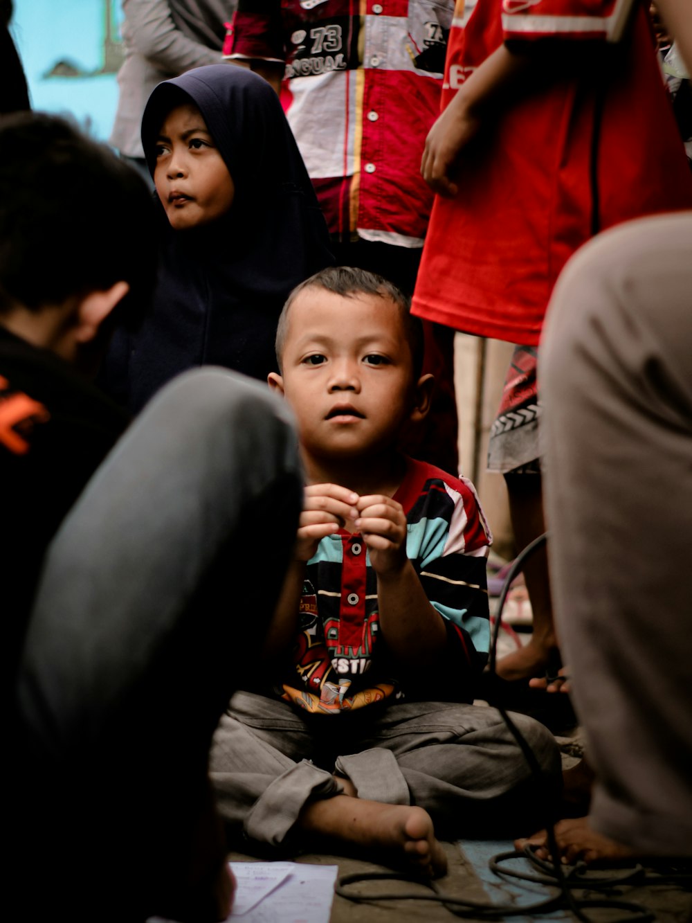 a young boy sitting on the ground in front of a group of people