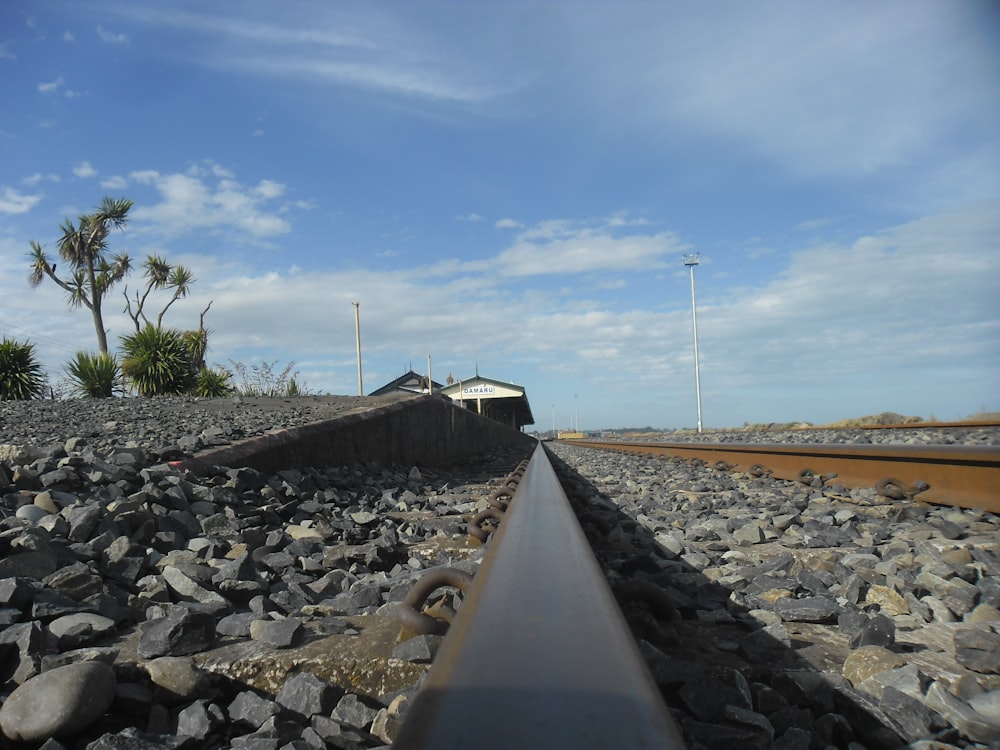 a train track with rocks and a building in the background