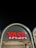 A modern architectural structure featuring an illuminated sign with the word 'YASA' in bold red letters. The sign is mounted on an arched facade that has a sleek, contemporary design with soft lighting accentuating its curves. The night sky provides a contrasting dark backdrop.