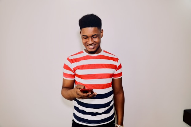a man in striped shirt holding a cell phone