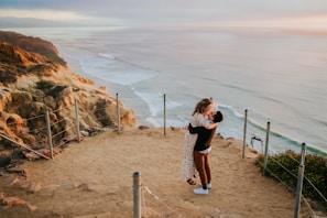 A couple embracing on a scenic coastal cliff.