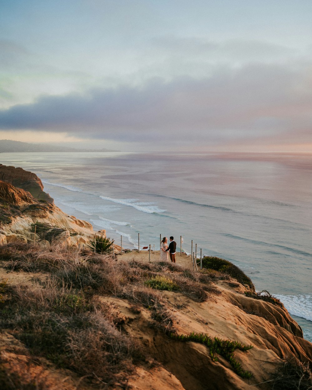 a couple of people standing on top of a cliff