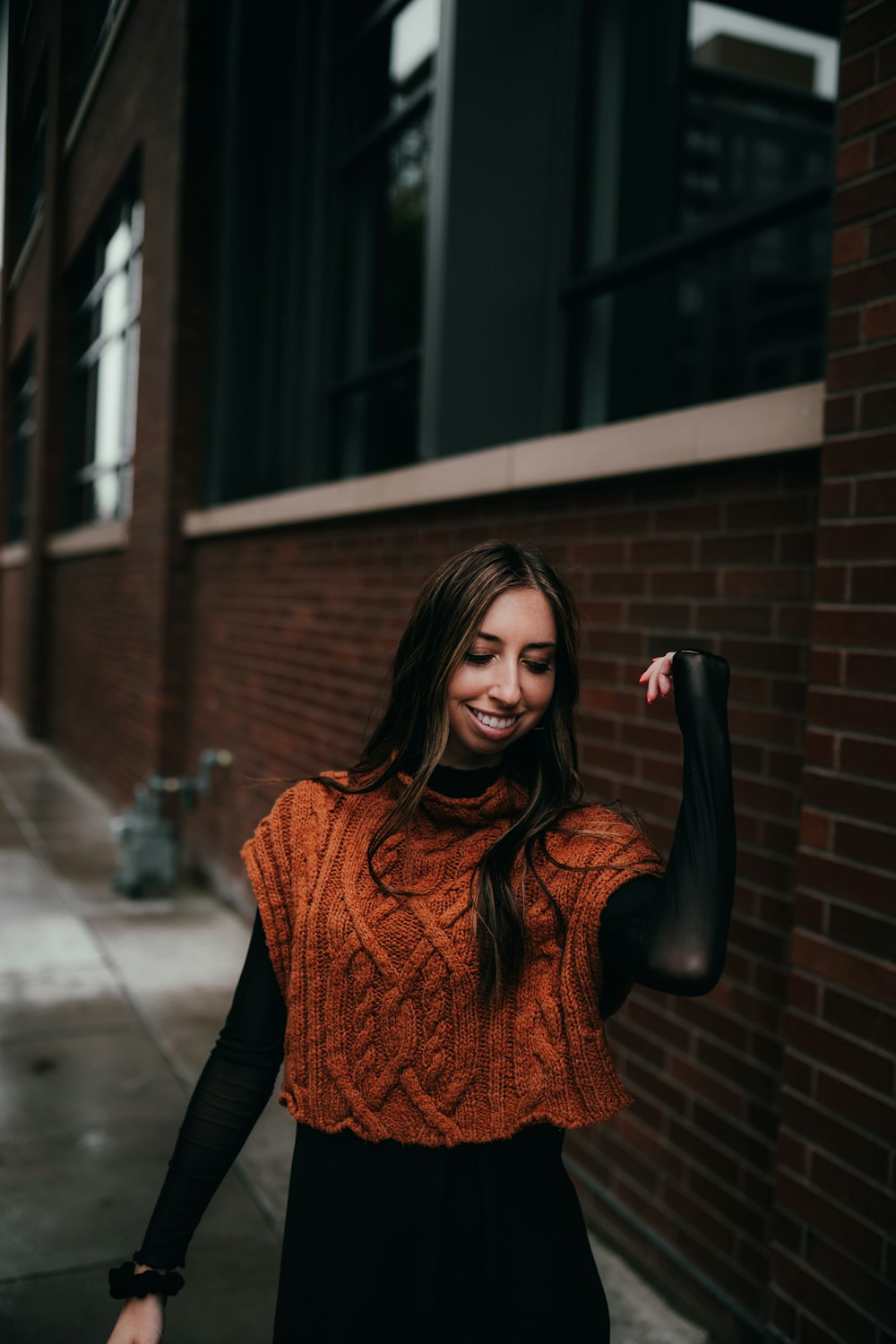 a woman in an orange sweater and black pants