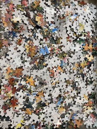 a pile of puzzle pieces sitting on top of a wooden floor