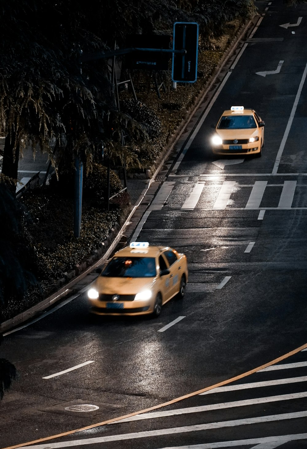 two taxi cabs driving down a street at night