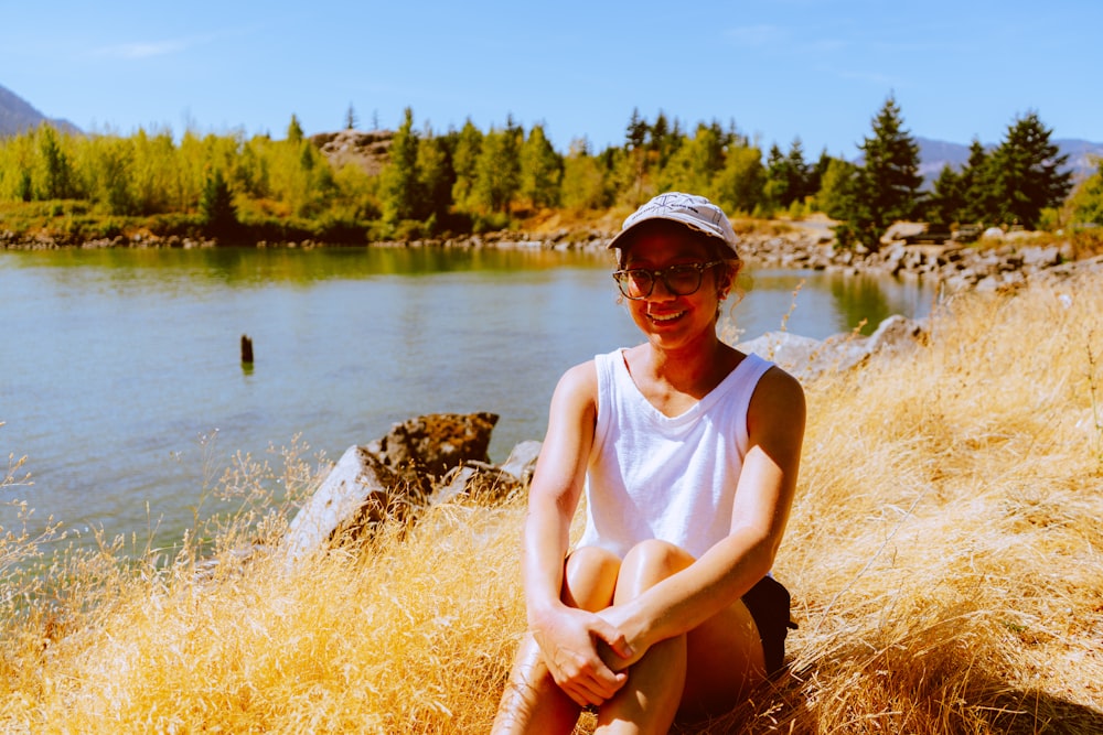 a woman sitting on a rock next to a lake