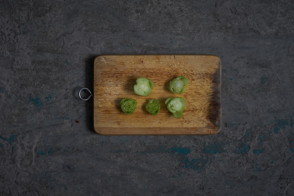 a wooden cutting board topped with green vegetables