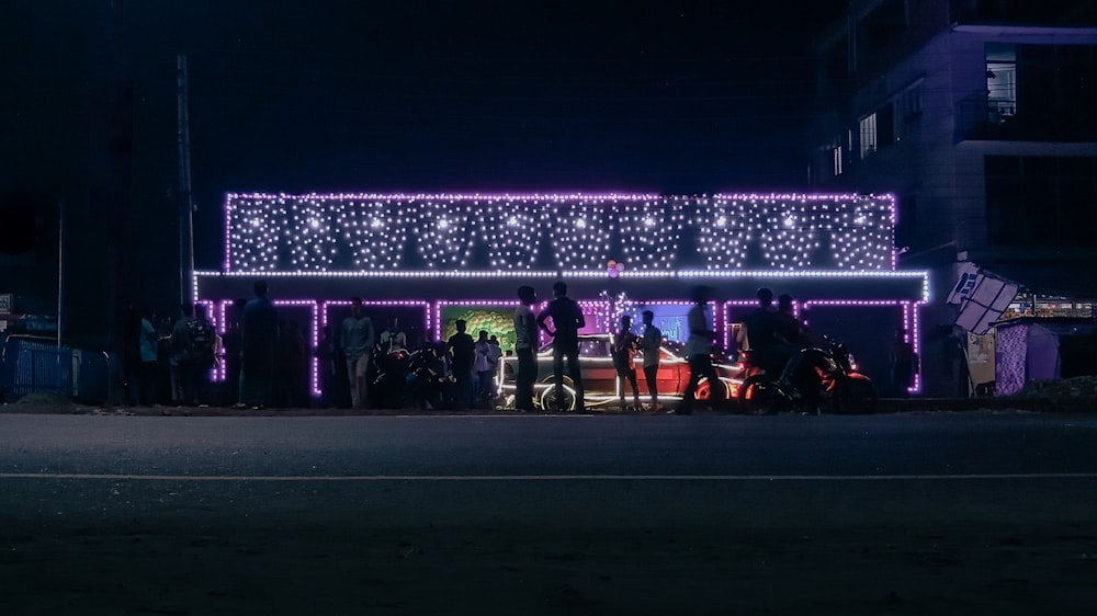 a group of people standing in front of a building covered in christmas lights