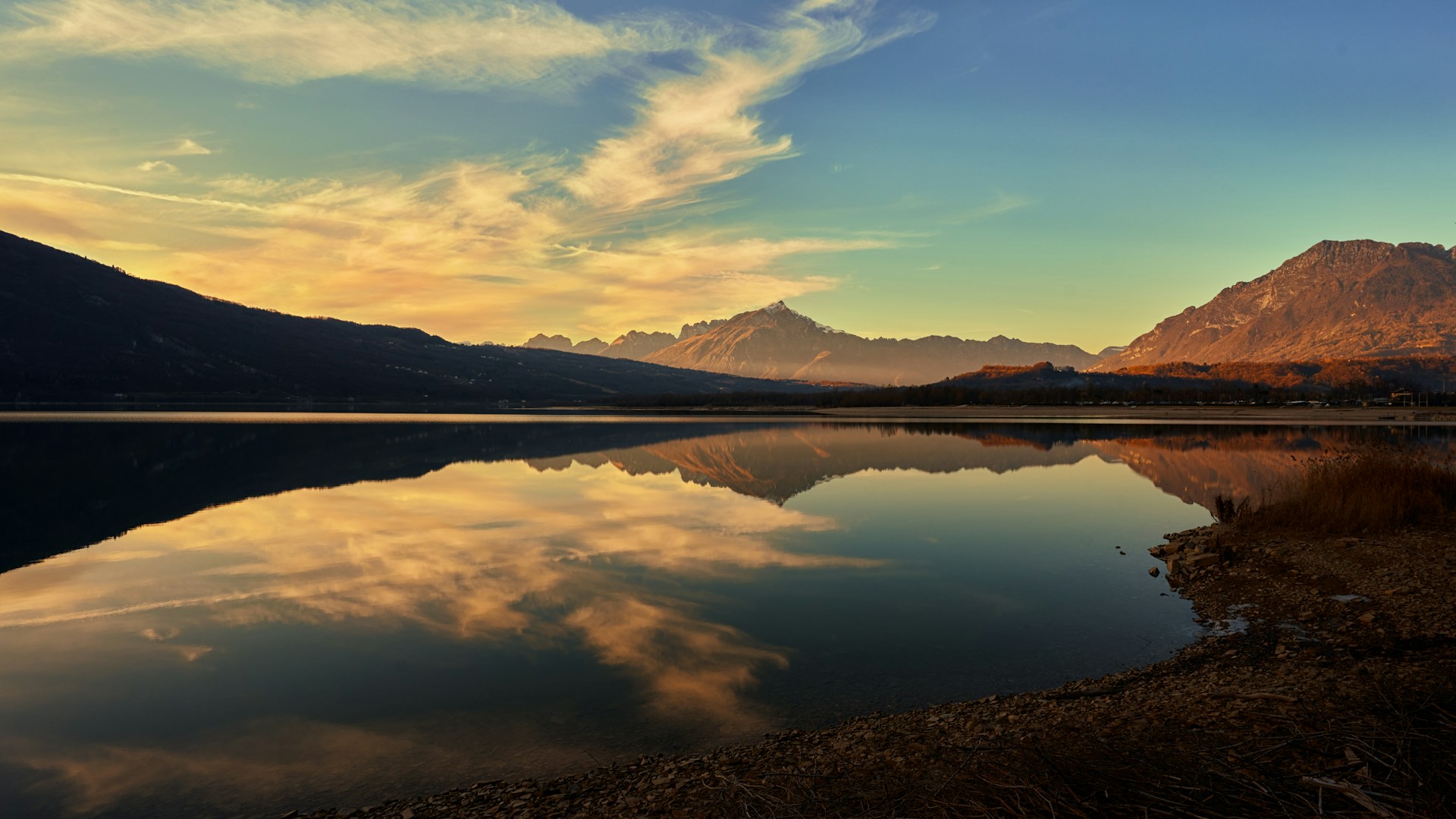 a lake with mountains in the background and clouds in the sky