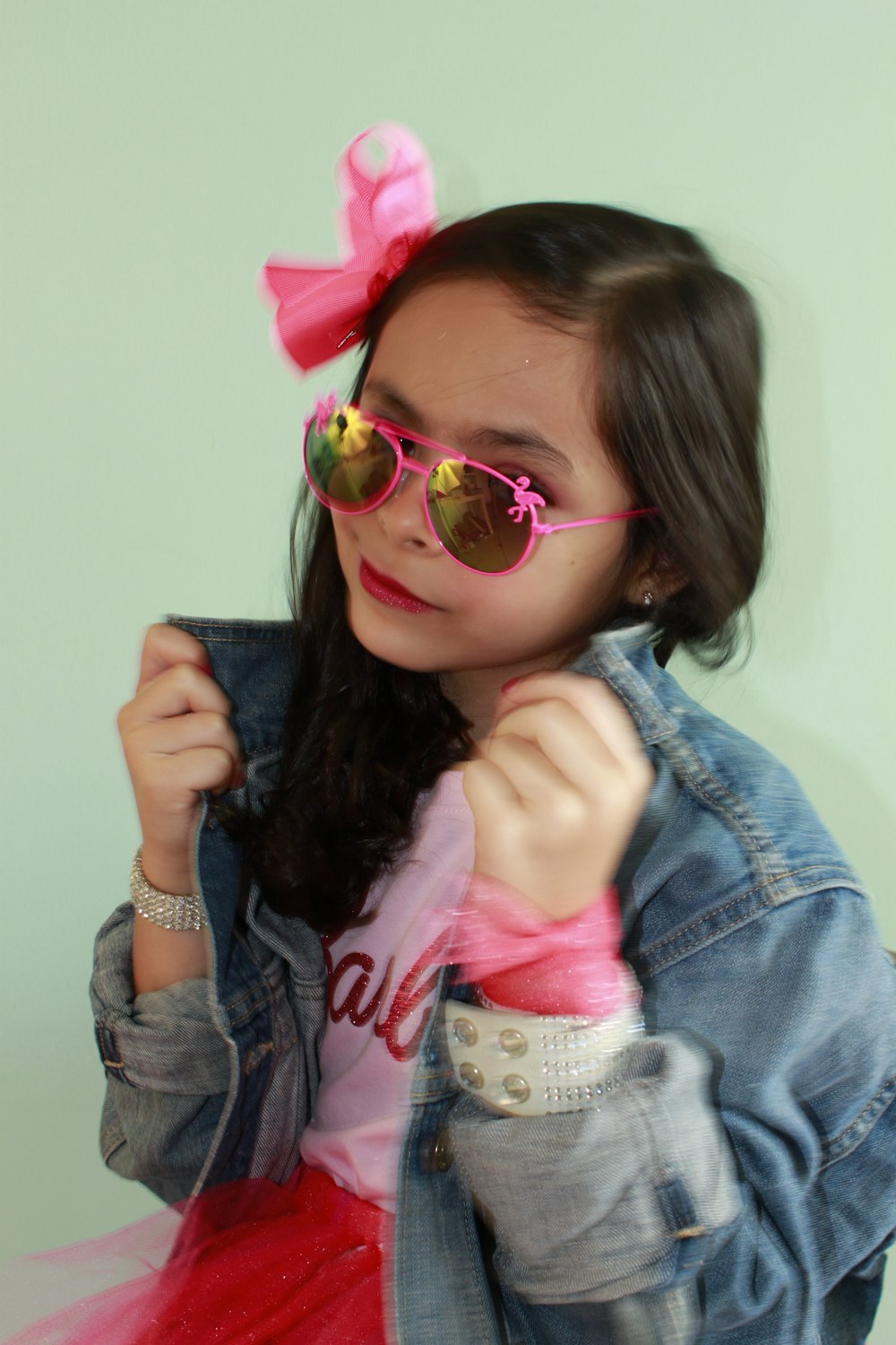 a little girl wearing pink sunglasses and a jean jacket