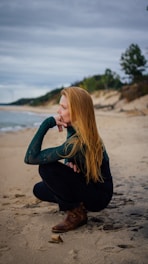 a woman sitting on a beach next to the ocean