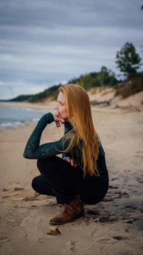 a woman sitting on a beach next to the ocean