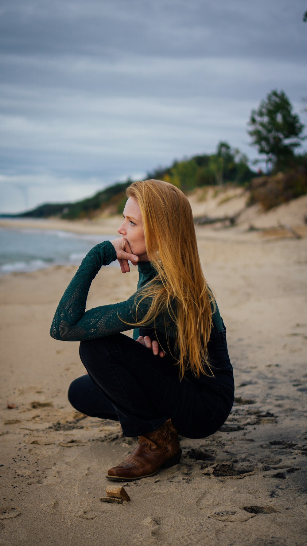 a woman sitting on a beach next to the ocean