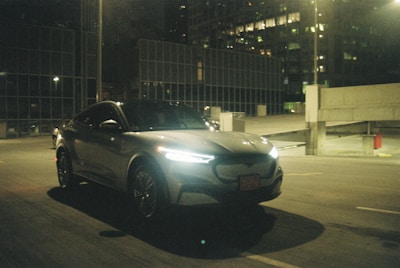 Sleek electric car gliding on a futuristic city street at dusk.