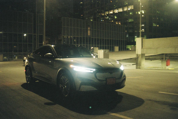 A sleek electric vehicle gliding through a futuristic cityscape illuminated by neon blue and green lights.