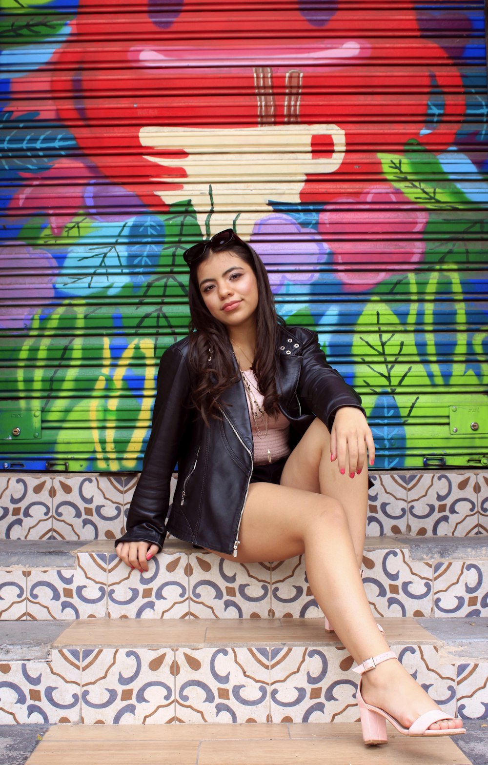 a woman sitting on a step in front of a colorful wall
