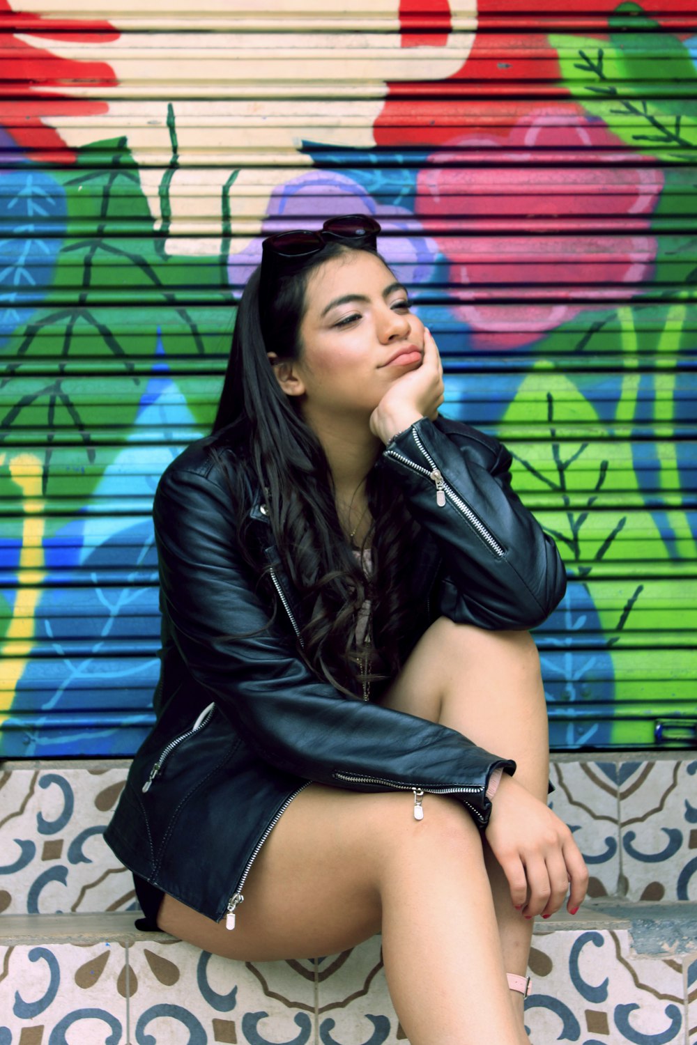 a woman sitting on a step in front of a colorful wall