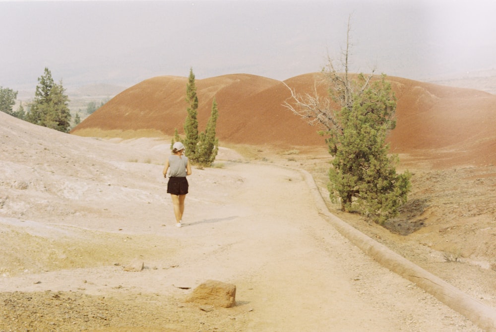 a woman running down a dirt road in the desert