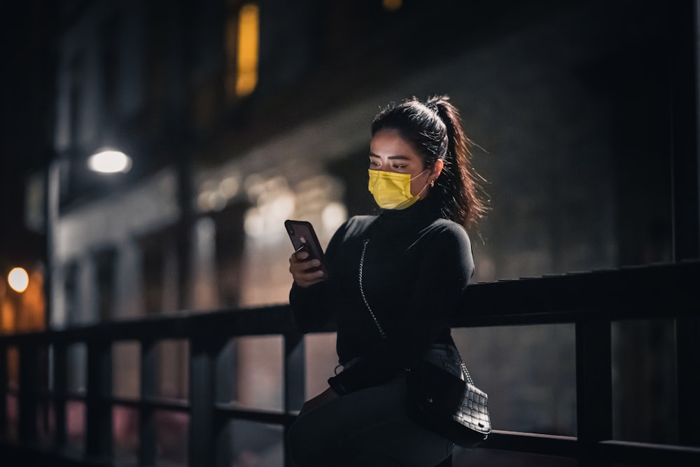 a woman wearing a face mask while looking at her cell phone