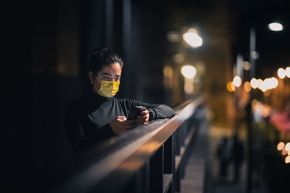 a woman wearing a face mask while looking at her cell phone