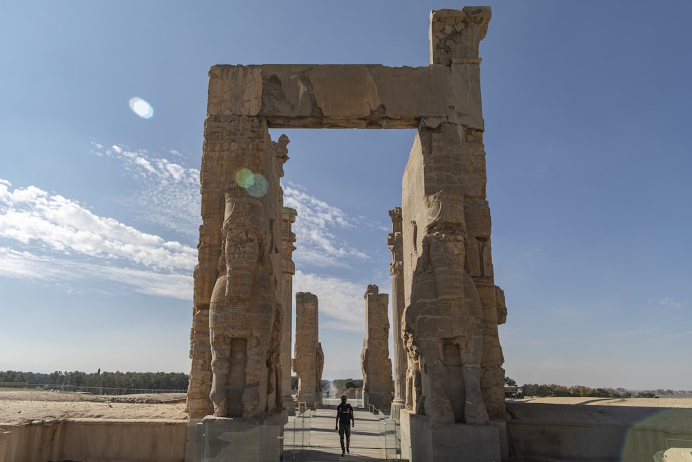 a person standing in front of a stone arch