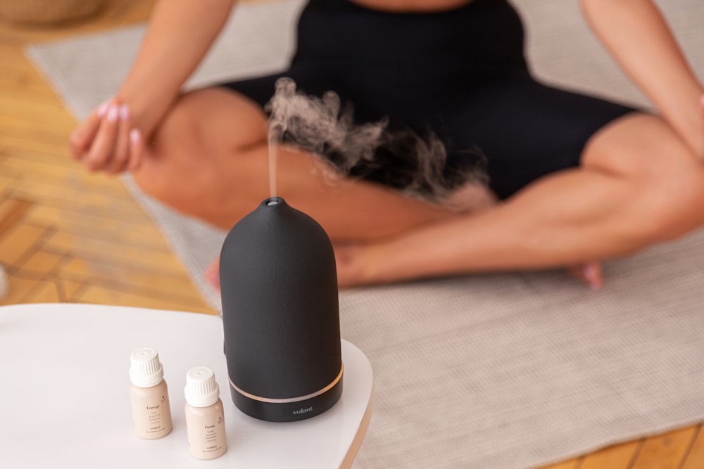 a woman sitting on a mat with a diffuser on top of her