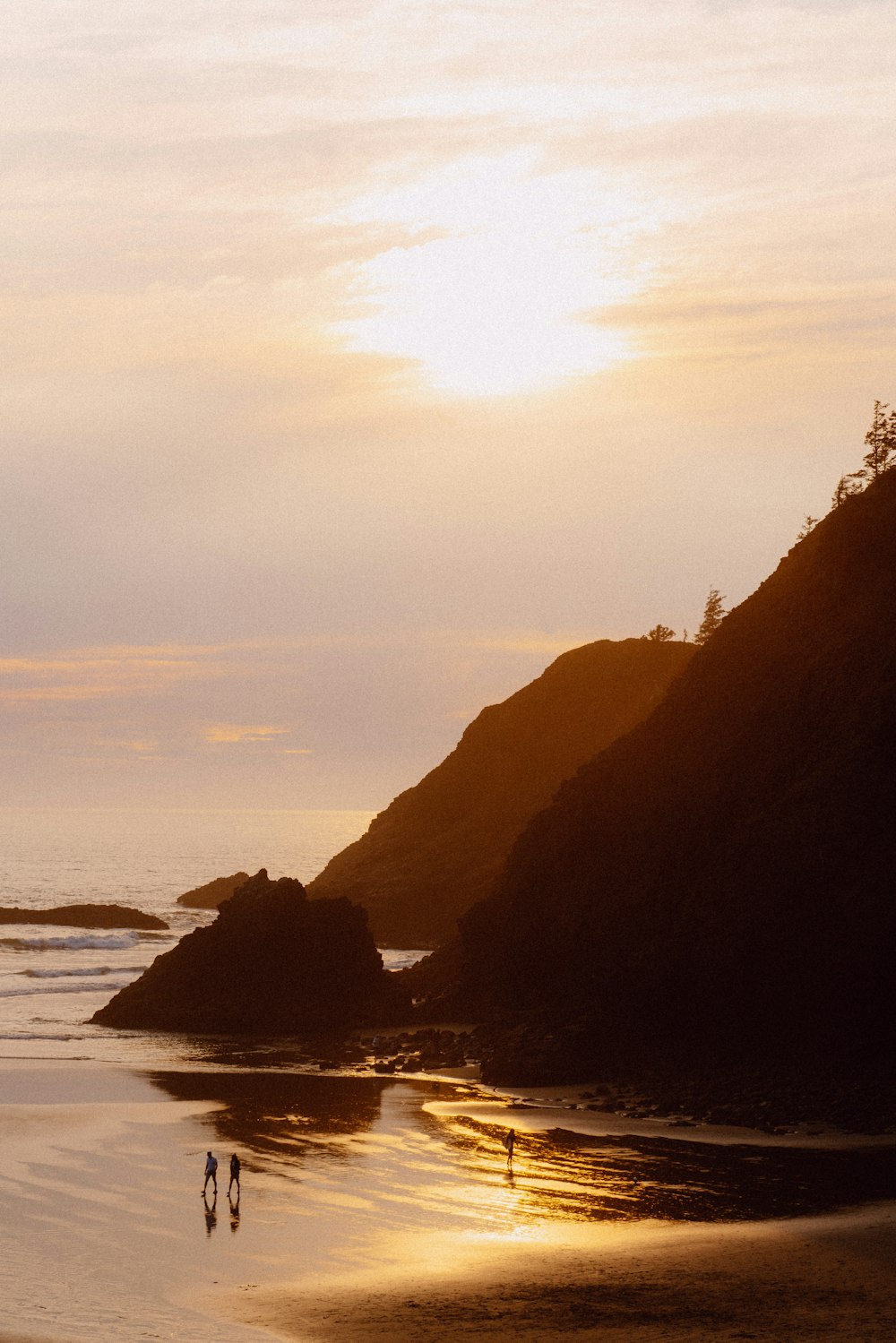 a couple of people walking along a beach near the ocean