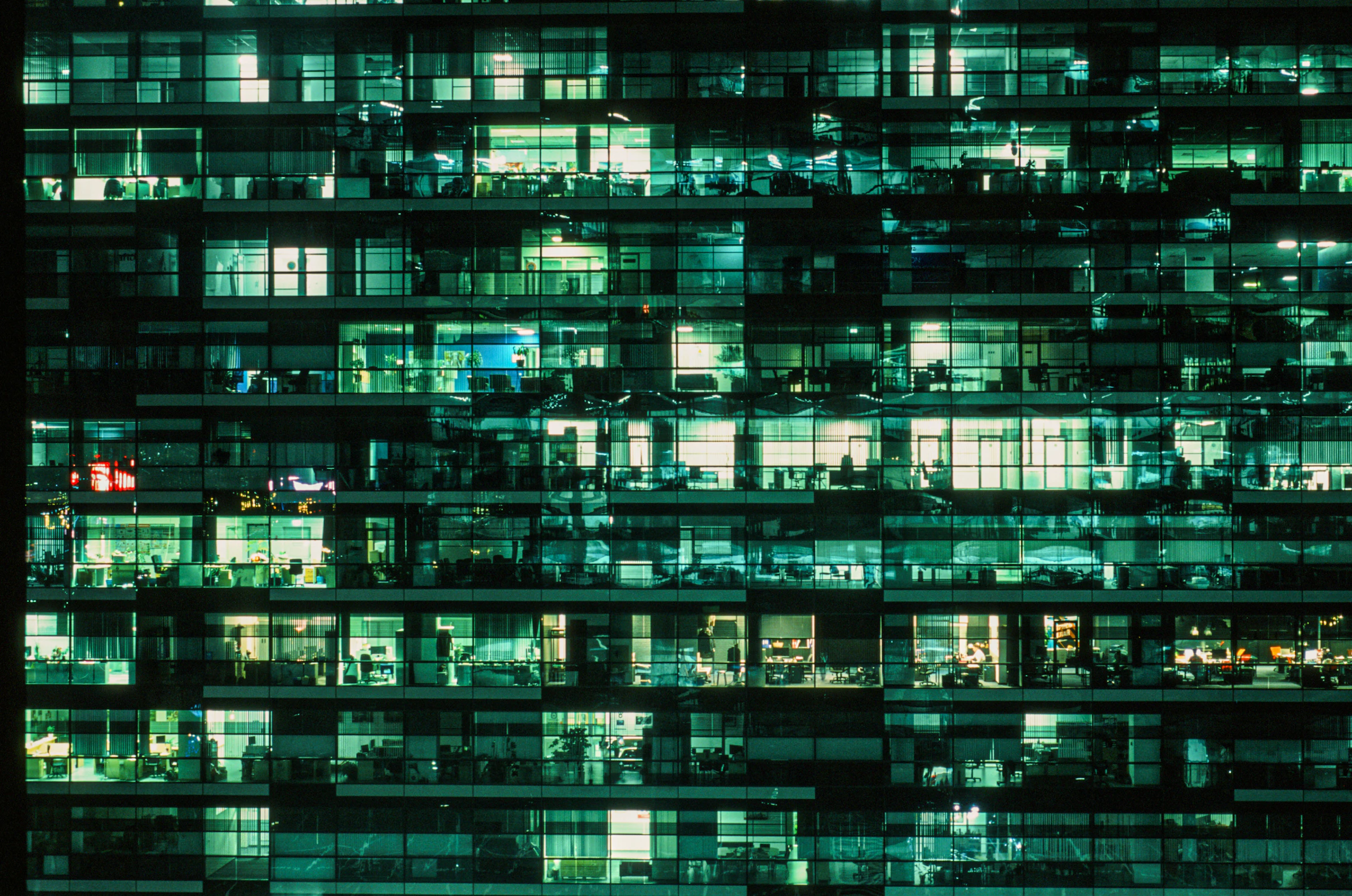 Une tour de bureaux aux fenêtres éclairées, la nuit
