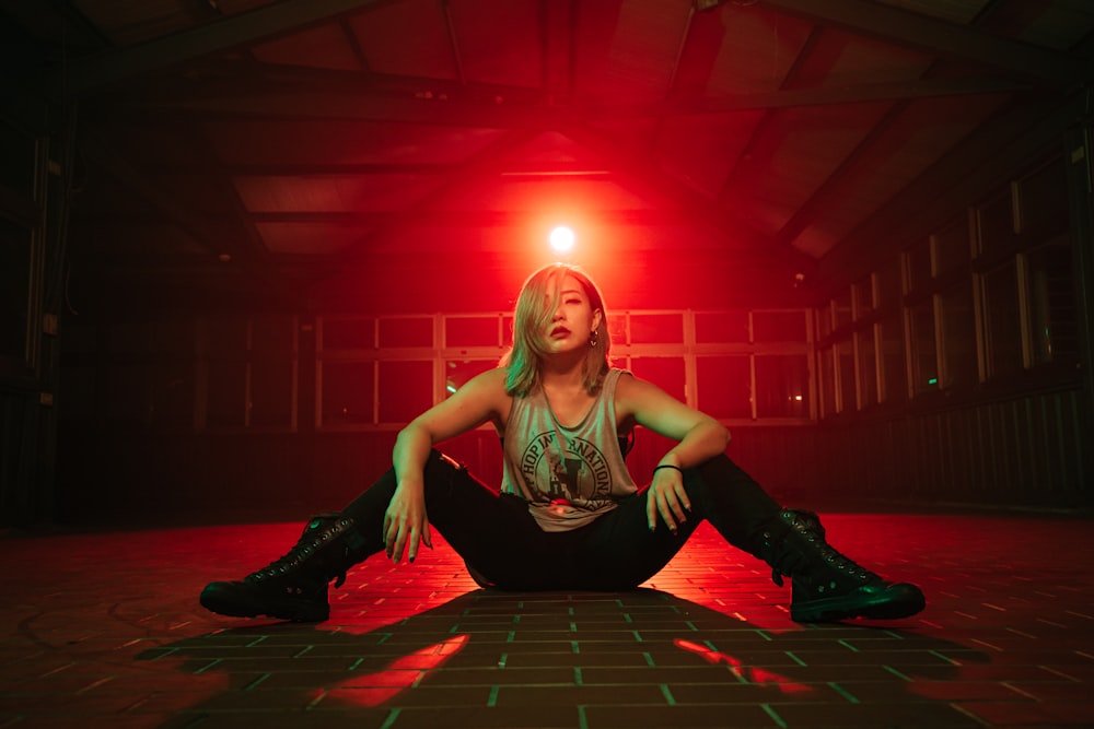 a woman sitting on the floor in front of a red light