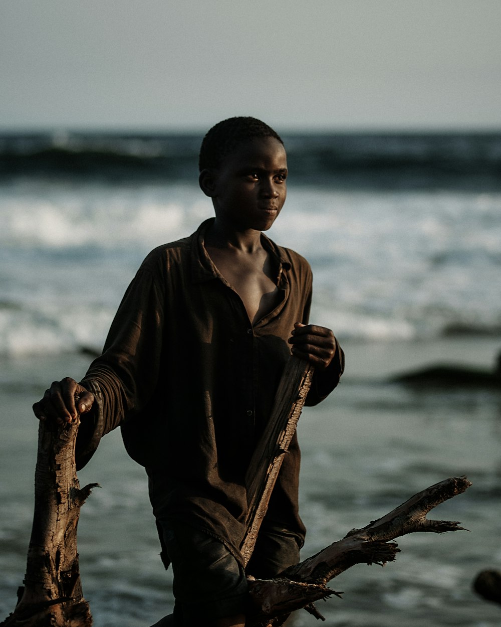 a young man standing on a beach next to the ocean