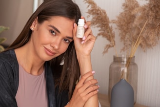a woman holding a bottle of lotion next to her face