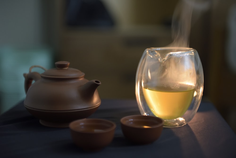 a glass of white wine next to a tea pot