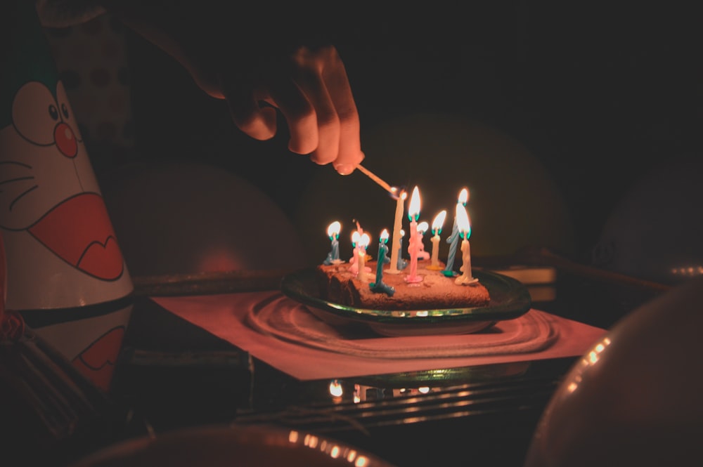 a person lighting candles on a birthday cake