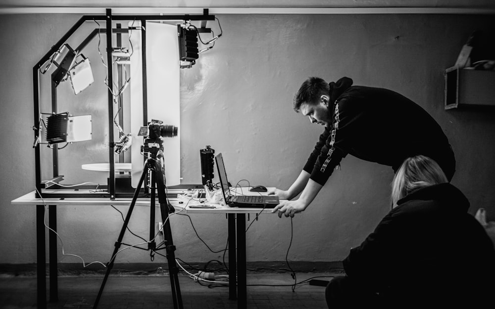 a man standing over a laptop computer on a table