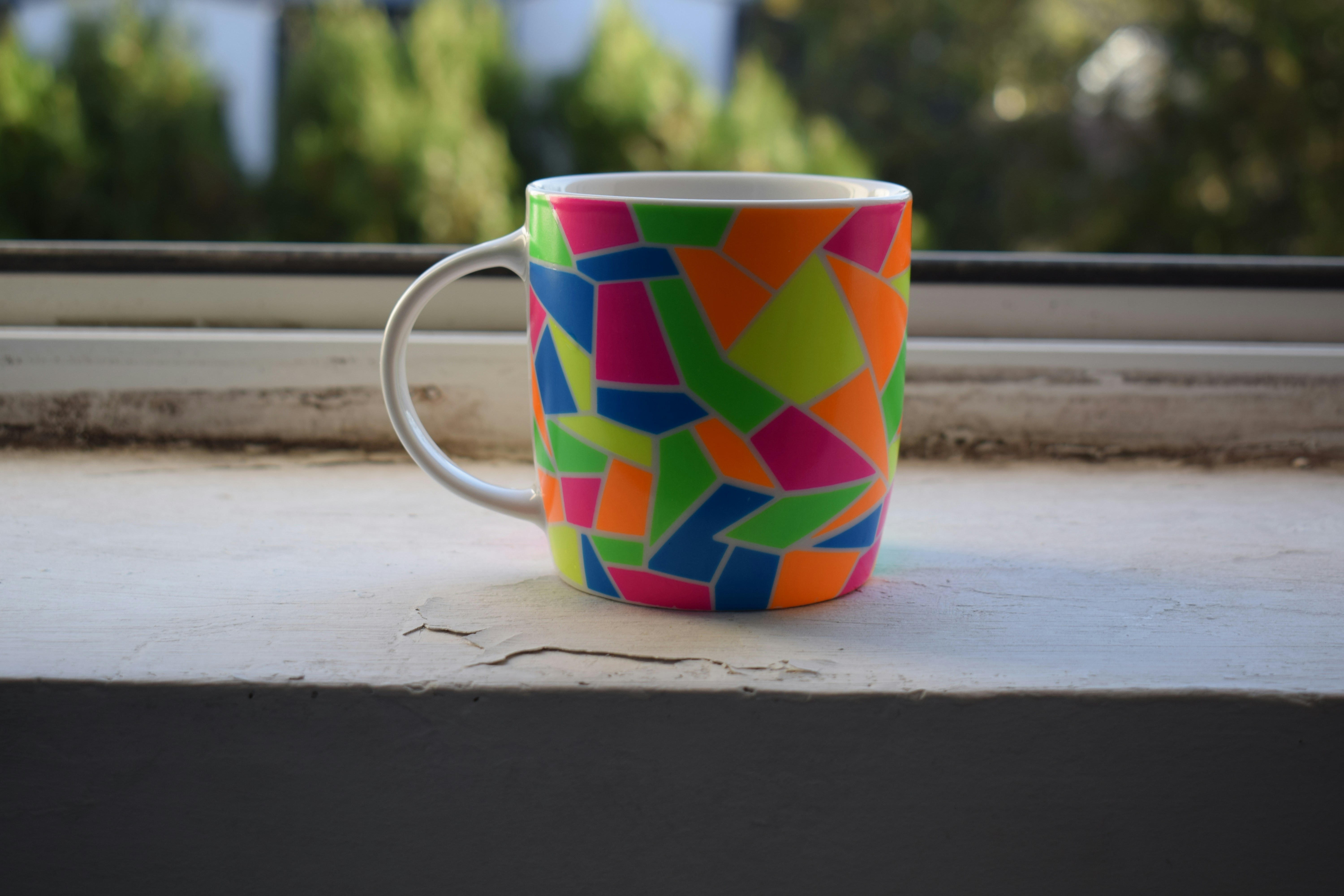 Coffee mug with clean geometric art pattern sitting upright, looks like tasteful desk decor, bright warm studio lighting