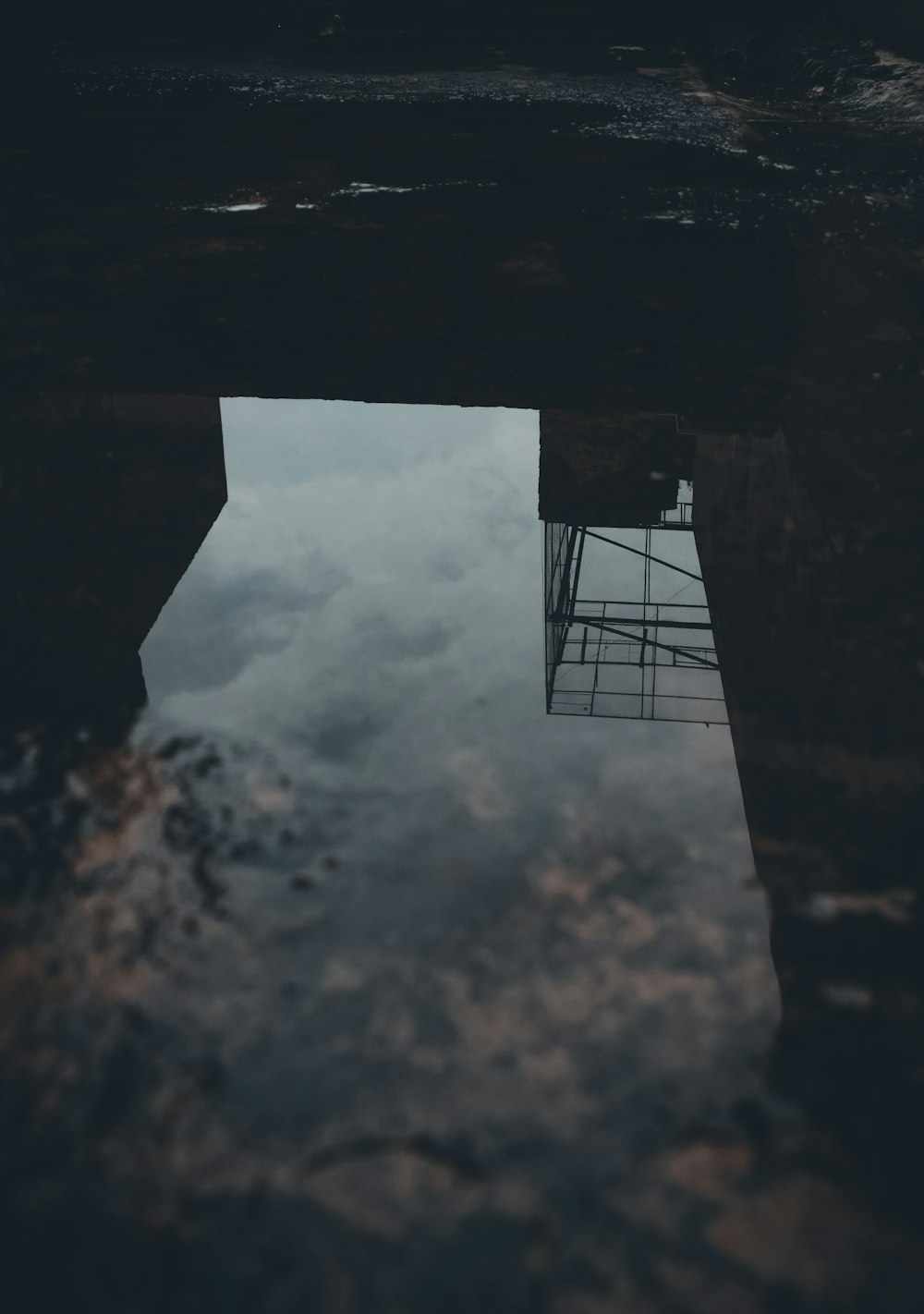 a reflection of a tower in a puddle of water