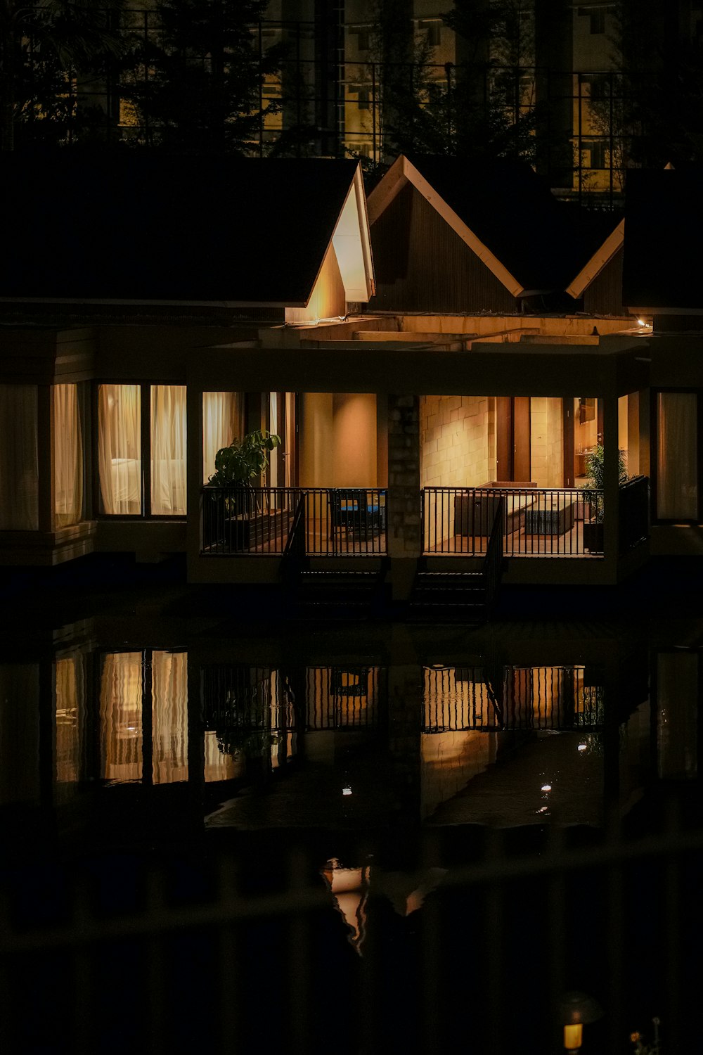 a house is lit up at night by the water