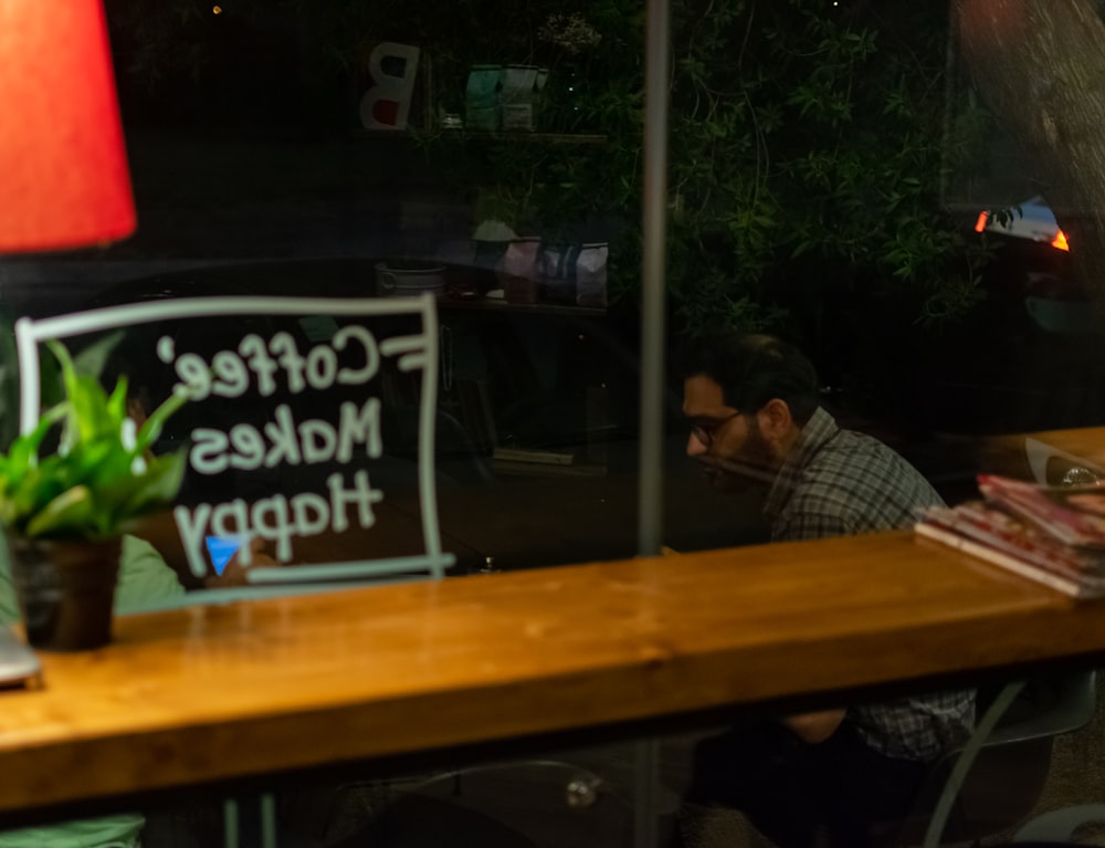 a man sitting at a table in front of a sign