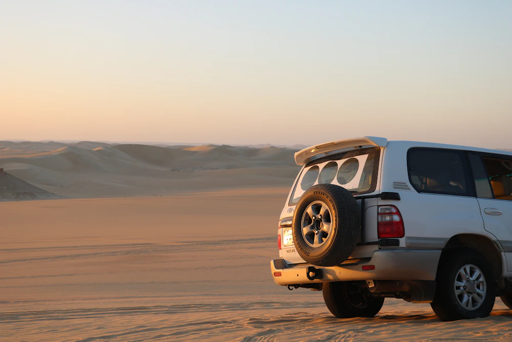 A vehicle driving through the desert at sunset