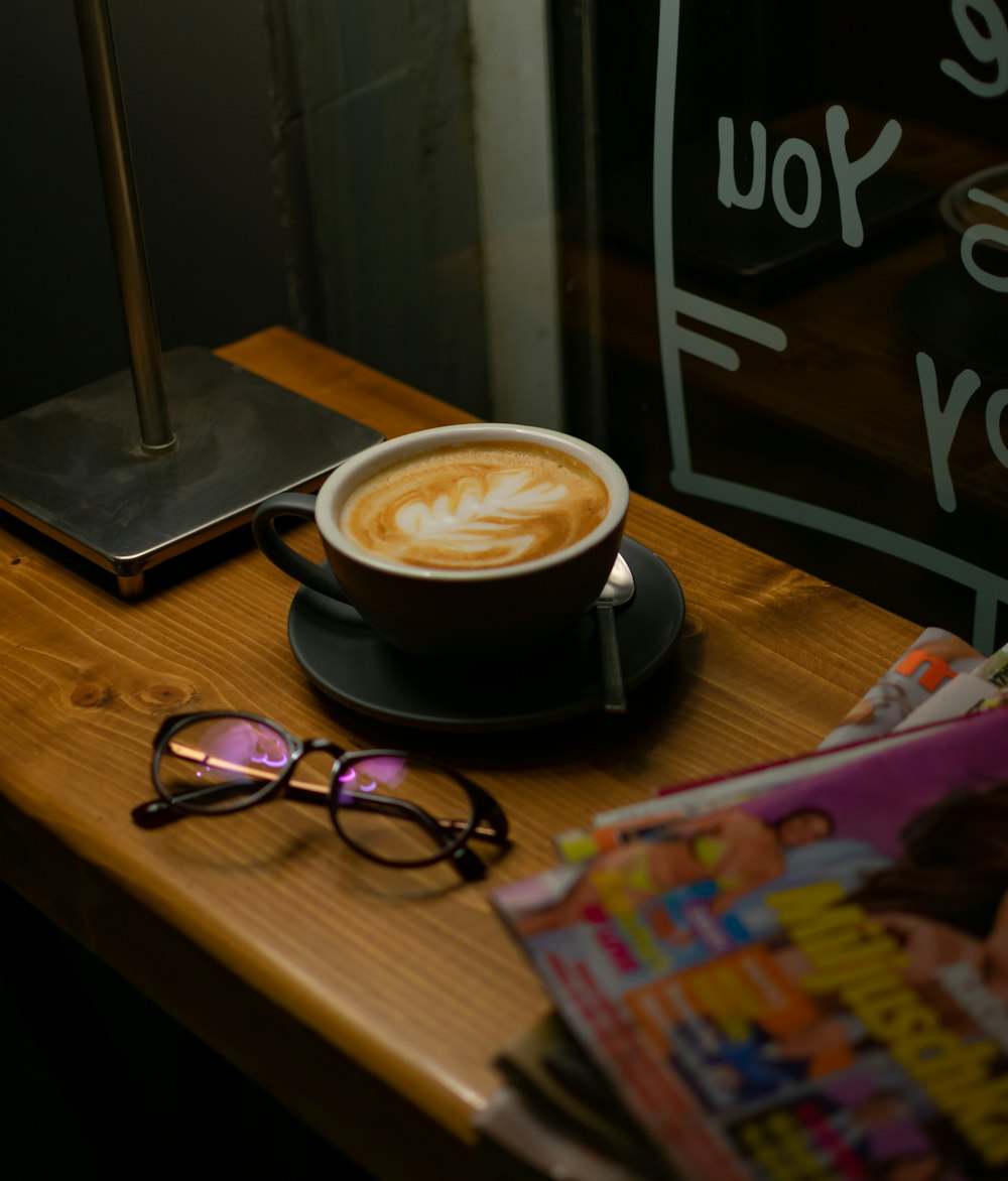 a cup of coffee on a table with a pair of glasses