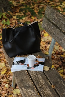 a black purse sitting on top of a wooden bench