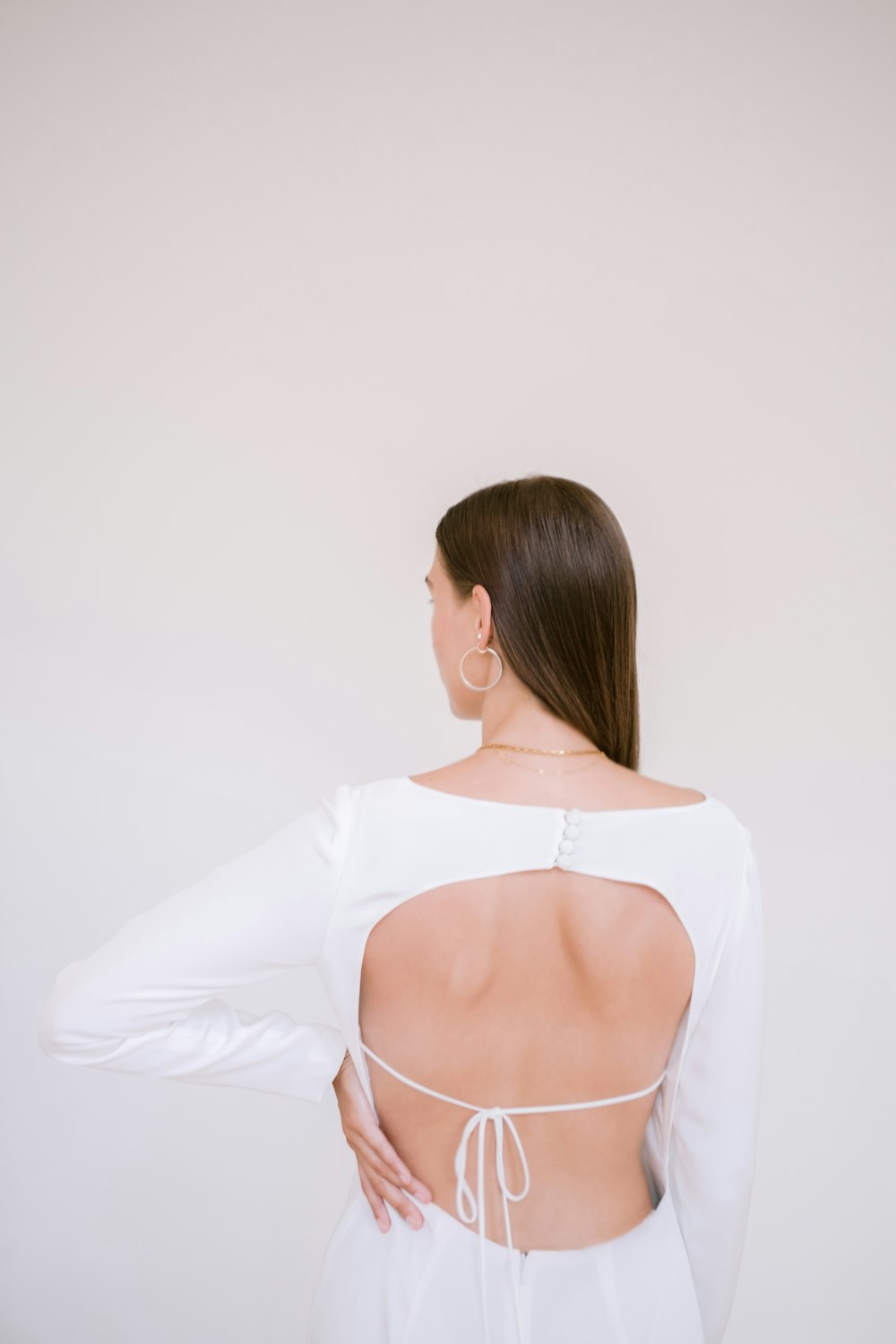 a woman wearing a white dress with a back cut out