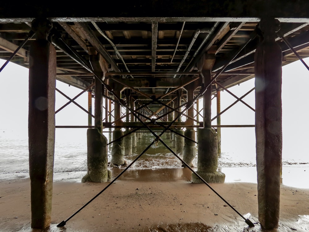 the underside of a pier on a sandy beach