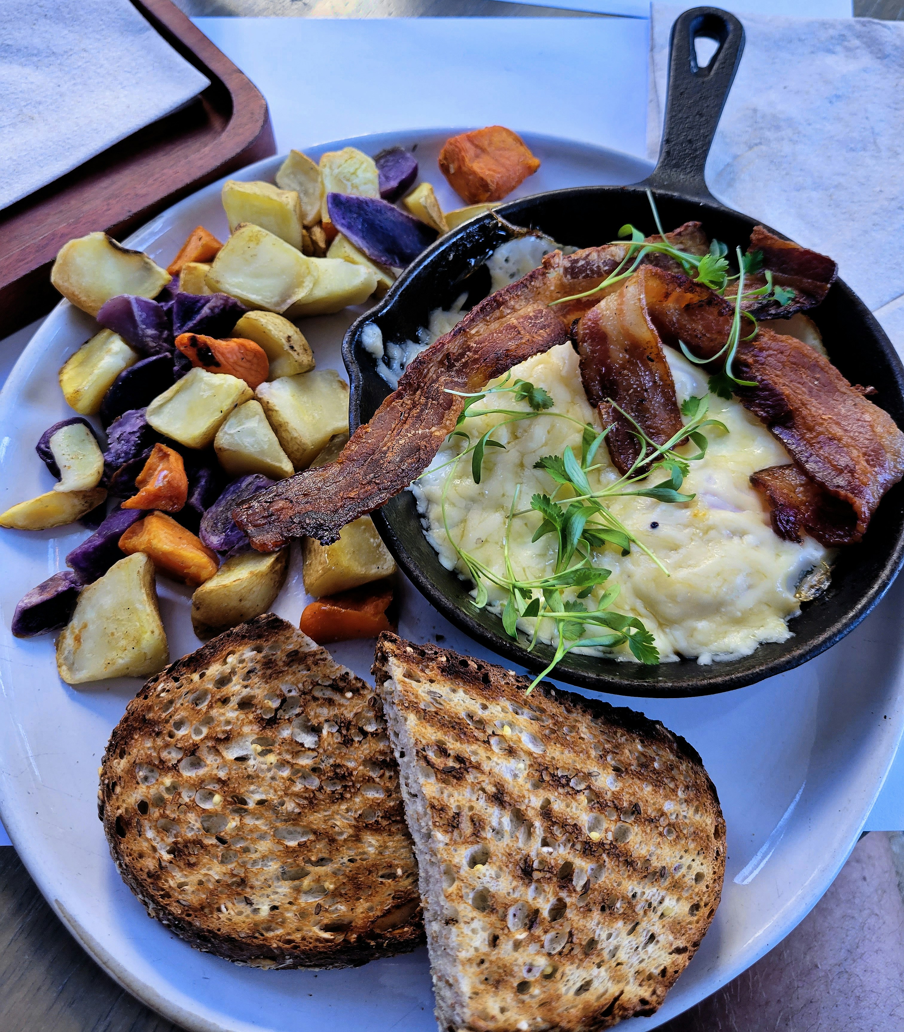 Toasted seeded burger buns in cast iron skillet with crispy bacon and mashed potatoes