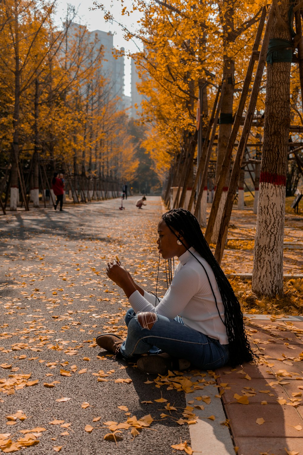 a woman sitting on the ground in a park