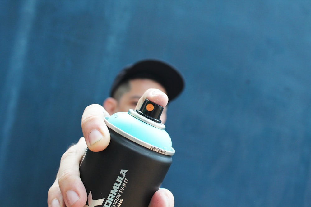 a man holding a black and blue spray can